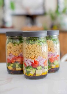 three mason jars filled with different types of salads and veggies in them