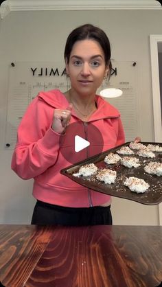 a woman holding a tray with cookies on it