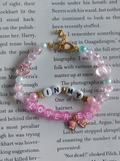 two bracelets with words and charms on top of an open page of a book