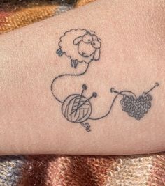 a tattoo on the arm of a person with a sheep and ball of yarn in it