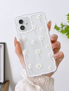 a person holding up a phone case with daisies on it