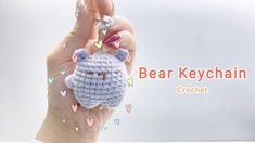 a hand holding a small crocheted animal keychain in front of a white background