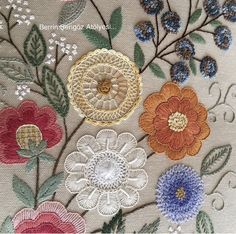 an embroidered piece with flowers and leaves on it's side, in various colors