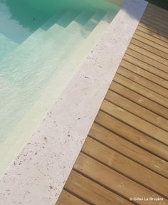 an empty swimming pool in the middle of a wooden decked area with clear blue water