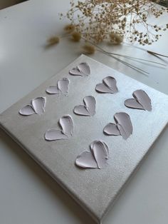 a canvas with hearts cut out of it sitting on a table next to dried flowers