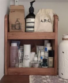 a wooden shelf filled with lots of personal care items next to a white vase and bag