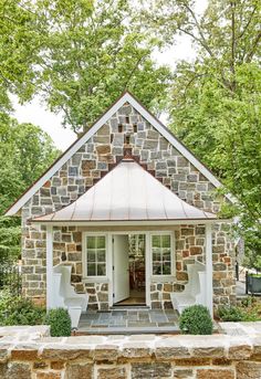 a small brick house with a white door and windows on the front porch, surrounded by trees