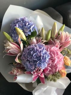 a bouquet of flowers sitting on top of a white wrapper next to a window