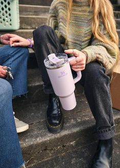 a woman sitting on steps holding a pink coffee cup