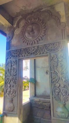 an intricately carved stone arch in the middle of a building with palm trees behind it