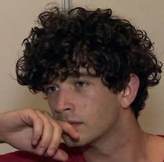 a close up of a person with curly hair and a tattoo on his left arm