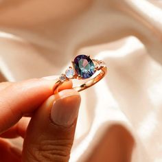 a woman's hand holding an engagement ring with a blue stone in the middle