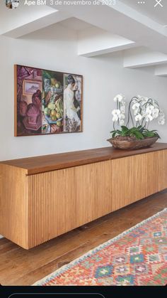 a large wooden cabinet sitting in the middle of a living room next to a painting