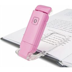 a pink pen sitting on top of an open book