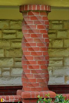 a cat sitting on top of a red brick pillar