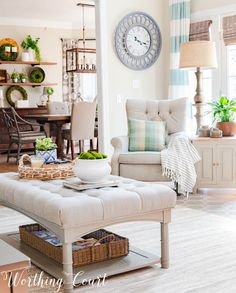 a living room filled with furniture and a large clock on the wall above the coffee table