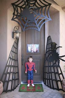 a little boy standing in front of a door with two spider webs on it