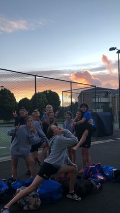 a group of young people standing on top of a tennis court next to each other