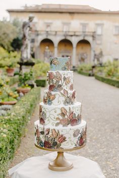 a three tiered cake sitting on top of a table in front of a building