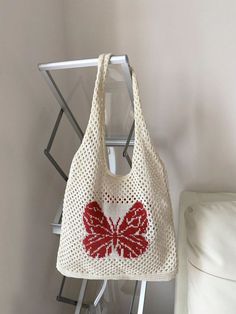 a crocheted bag with a red butterfly on it sitting next to a white chair