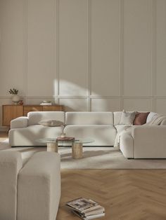 a living room with white furniture and wood floors