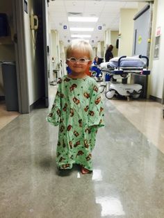 a little boy wearing glasses standing in a hospital hallway