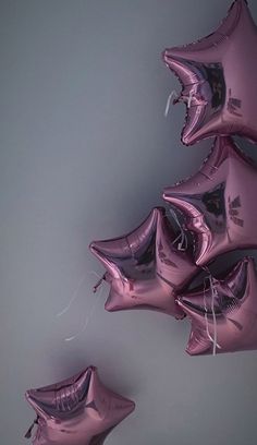 pink foil balloons in the shape of stars are arranged on a gray background with white string