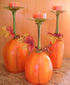 three pumpkin shaped candlesticks sitting on top of a counter