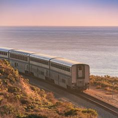 a train traveling down tracks next to the ocean