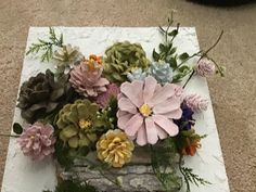 an arrangement of flowers is placed on top of a piece of paper that sits on the floor