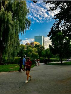 people are walking around in the park on a sunny day with blue skies and white clouds