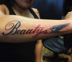 a woman with a tattoo on her arm holding a knife and the word beauty written in cursive writing