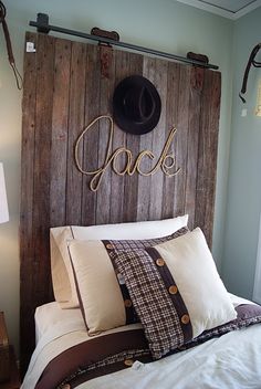 a bed that has some pillows on it and a hat hanging above the headboard