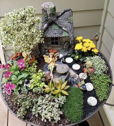 a table topped with lots of different types of flowers and plants next to a house