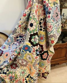 a multicolored quilt hanging on a wall next to a dresser