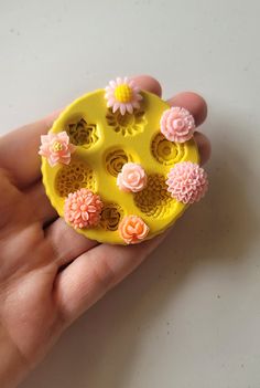 a hand holding a yellow plastic object with flowers on it