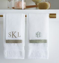 two white towels hanging on a towel rack with personalized monogrammed towels in front of them