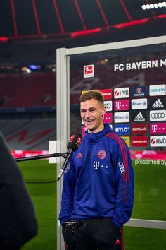 a man standing in front of a microphone on top of a soccer field at night