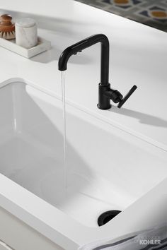 a white sink sitting under a faucet next to a counter top with soap dispenser