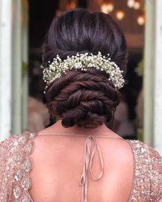 the back of a woman's head wearing a braid and flowers in her hair