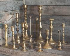 an assortment of brass candlesticks on a wooden table