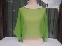 a mannequin wearing a green top in front of a window