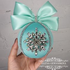 a hand holding an ornament with a snowflake decoration on it's side