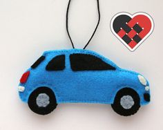 a blue car ornament hanging from a string with a heart on it's side