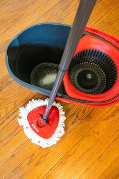 a mop is being used to clean a wooden floor with a red duster