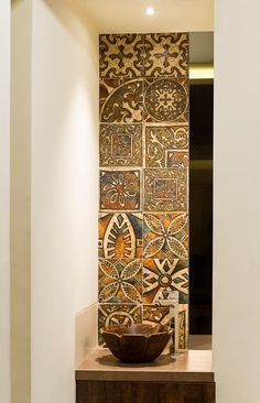 a bowl sitting on top of a wooden table in front of a wall covered with tiles