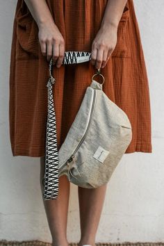 a woman in brown dress holding a purse with her hand on the side and white shoes