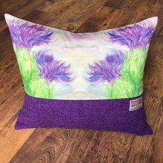 a purple and green pillow sitting on top of a wooden floor