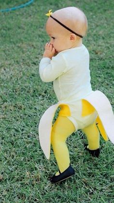 a baby dressed as a banana is standing in the grass