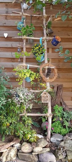 a wooden ladder made out of branches with plants growing on it and rocks in the foreground